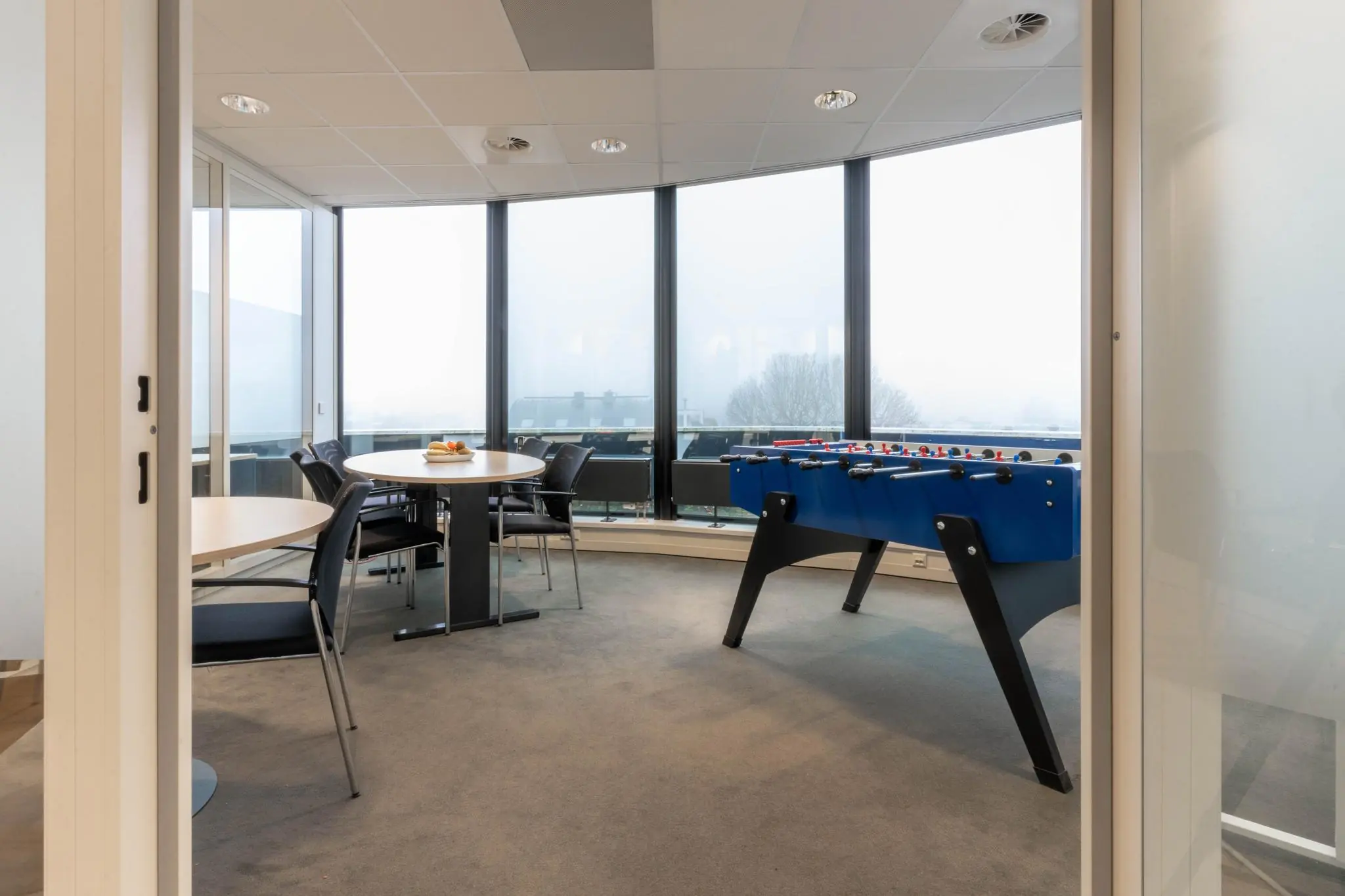 Moderne ontspanningsruimte met zithoeken en een blauwe tafelvoetbaltafel in een kantoor aan de 1e Hogeweg.